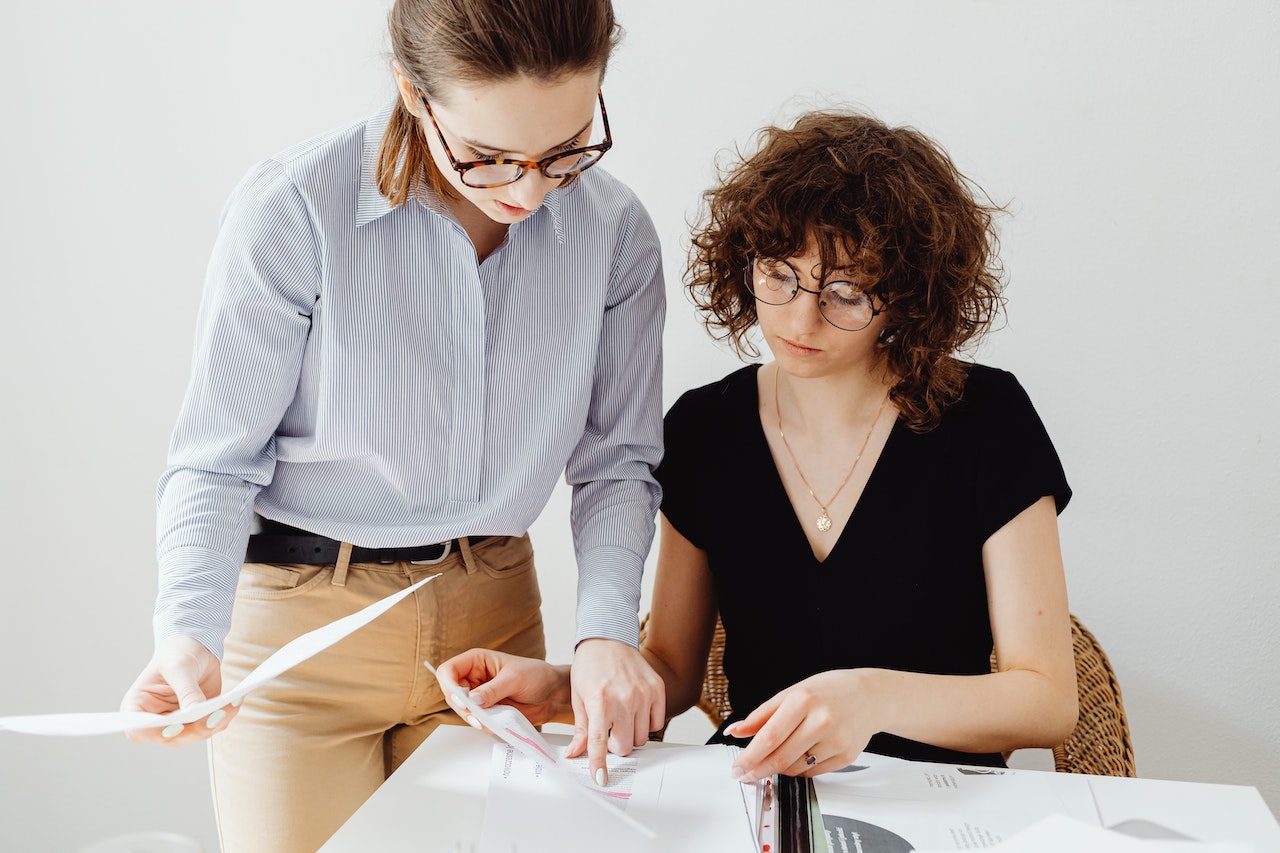 Two young bookkeepers compare notes on bookkeeping processes and best practices